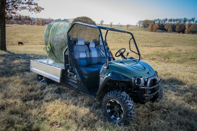 Classic with truck bed hauling hay bale; green